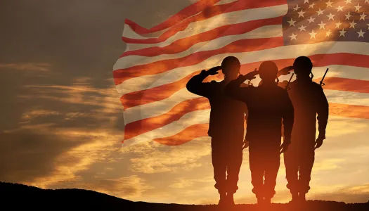 service members saluting at flag