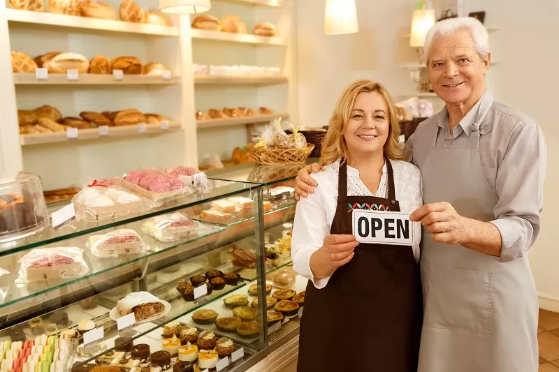 Bakery shop with two people holding an "OPEN" sign